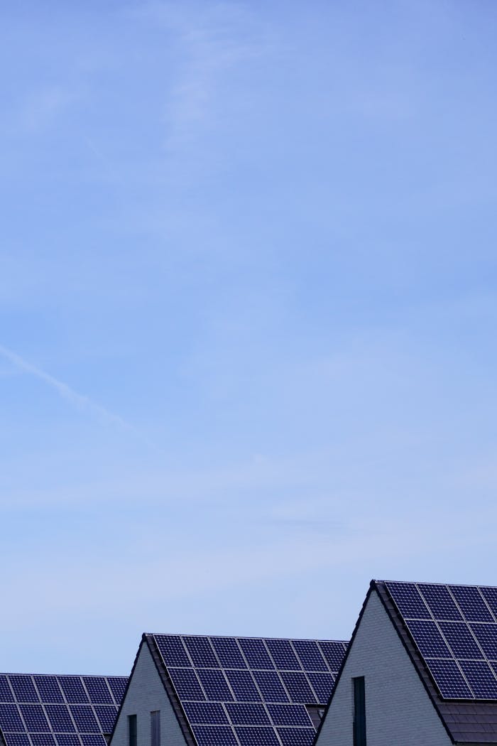 Modern residential houses with solar panels under clear blue sky, promoting renewable energy.